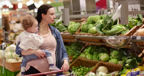 Mother and daughter buying vegetables in grocery store