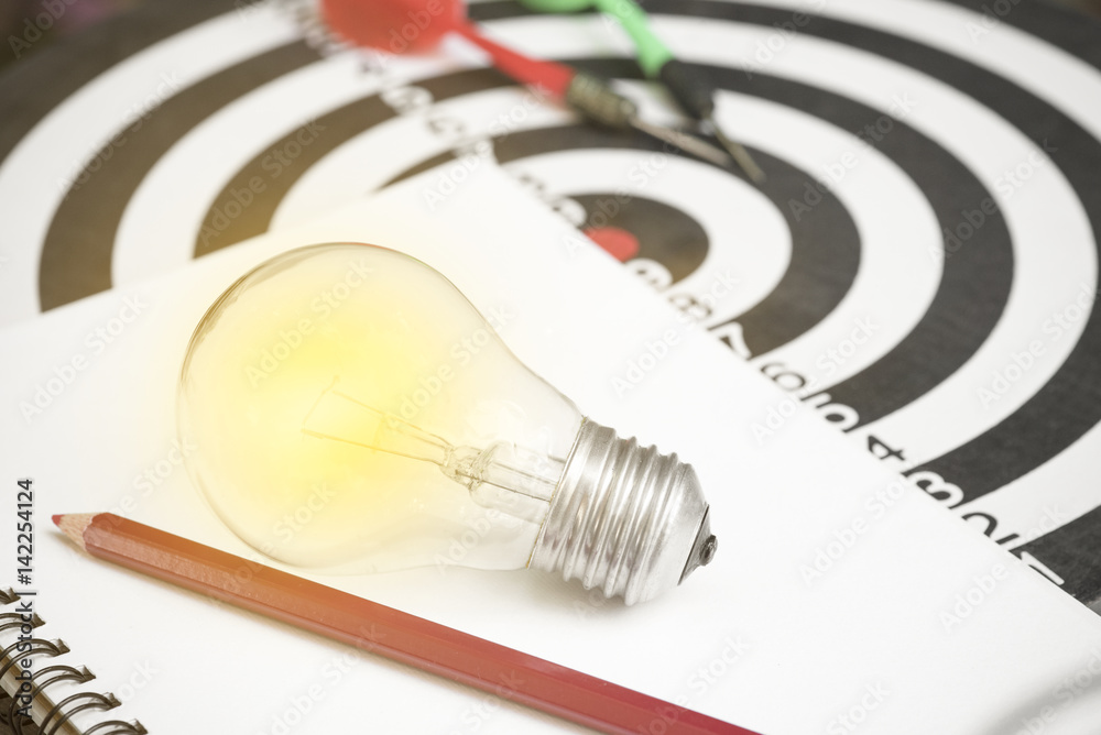 lightbulb on paper book and dartboard with arrow. concept for new ideas with innovation and creativity. lightbulb on paper book and dartboard with arrow. concept for new ideas with innovation and creativity.
