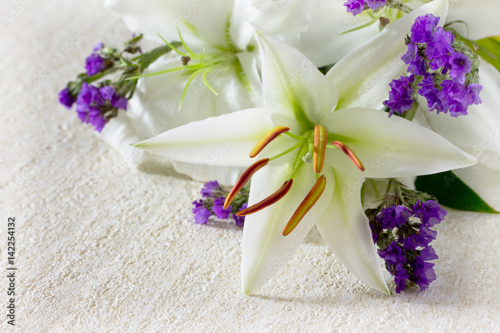 Wedding or birthday background. Beautiful fresh white lily flowers on a stone background. Copy space. Wedding or birthday background. Beautiful fresh white lily flowers on a stone background. Copy space.