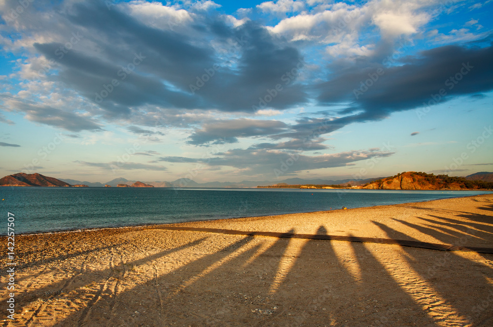 Mystical shadows on sandy sea beach in dawn sky background