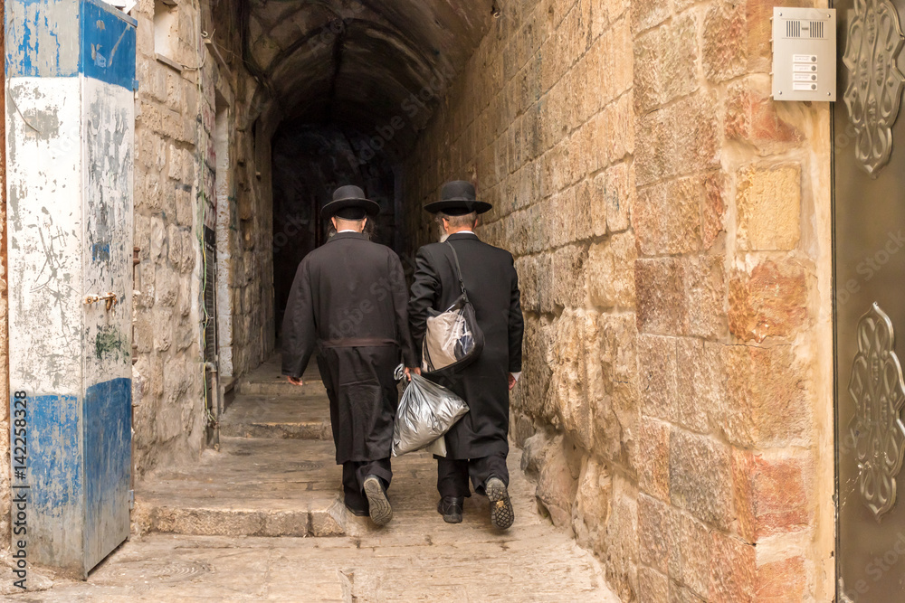 A narrow street in East Jerusalem with a couple of religious Jews.