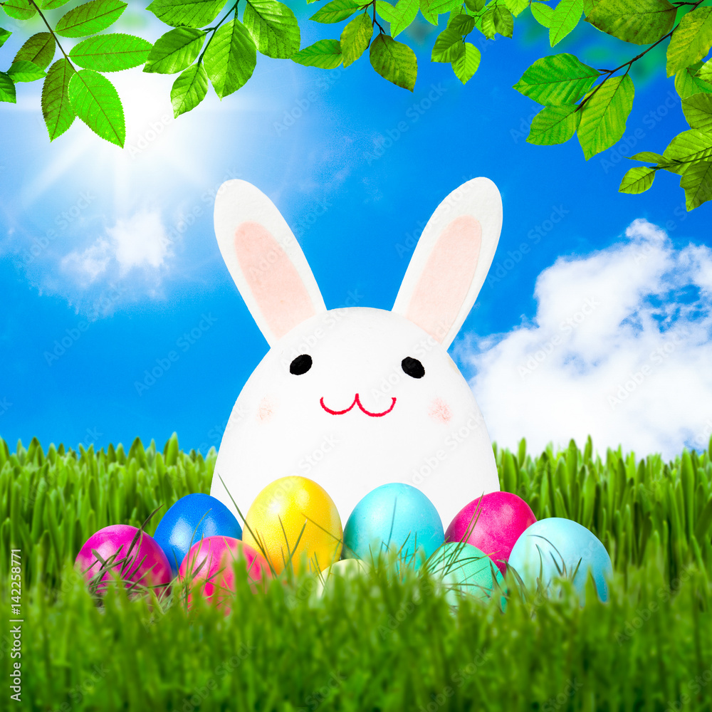 Lustiger Osterhase sitzt auf einer Wiese mit Ostereiern Stock Photo