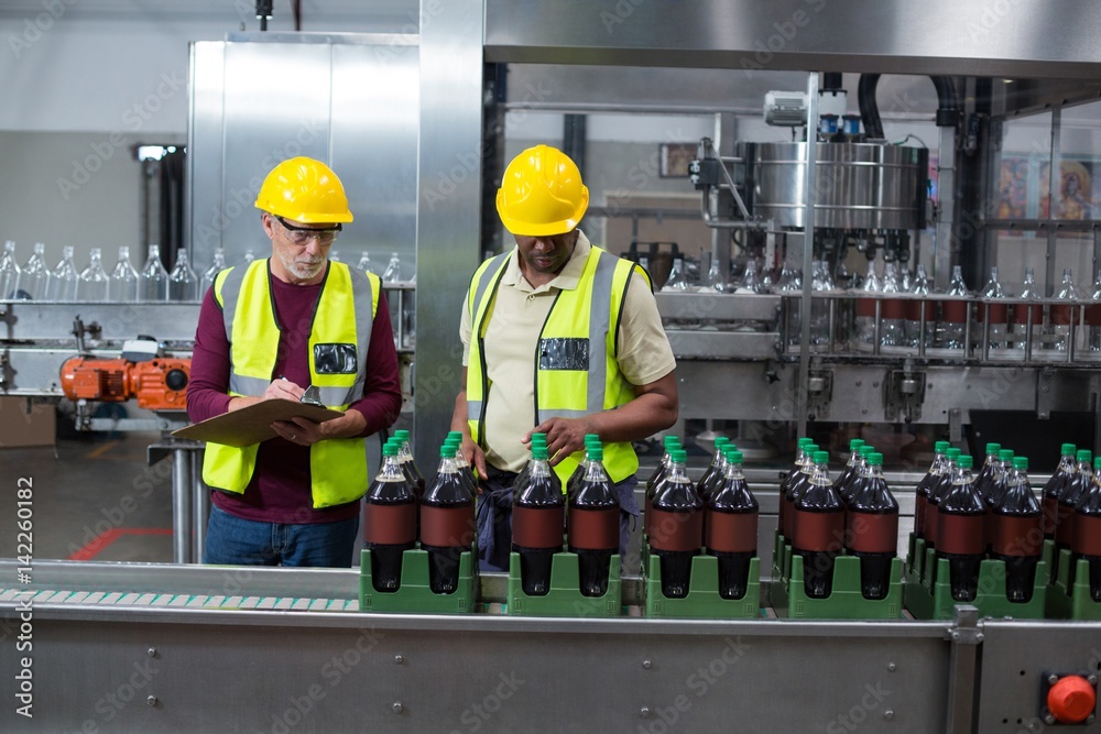 Εκτύπωση καμβά Two factory workers monitoring cold drink bottles in the plant