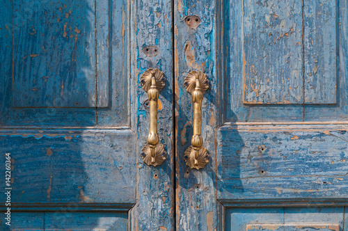 Architectural detail of a vintage brass door handle ,vintage antique door handle on the old blue wooden door