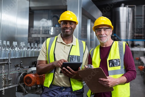 Factory workers with clipboard and digital tablet 