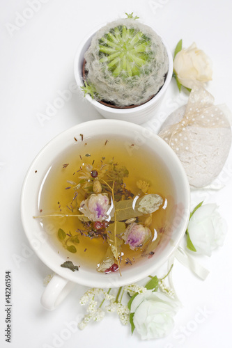 Green yellow white natural herbal tea harvested on plantations of bio eco healthy brewed in a cup. Mint lime-tree linden berries whole buds of roses petals welded in cup home love surprise background.
