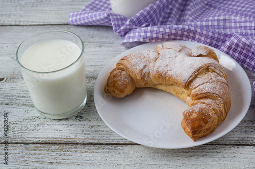 Croissant with milk on old wooden table for breakfast background.