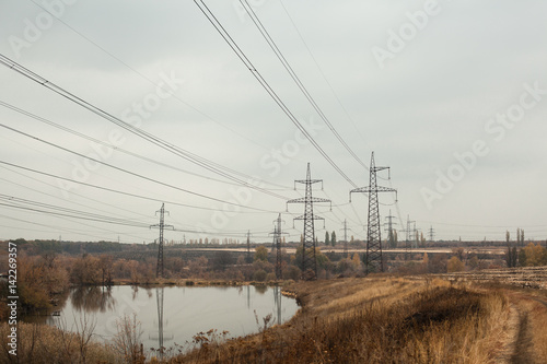Coal power station in beautiful area full of trees and lake, mirror reflection of energetic pole and power station with chimneys, synergy of industry and nature