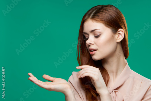 Green background, woman looks at her palm, light clothes