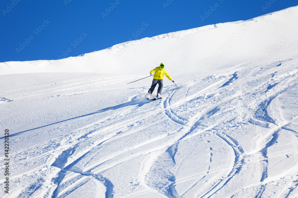 Male skier running downhill on slope at sunny day
