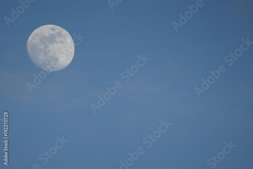 Weißer Mond bei Tag vor blauem Himmel