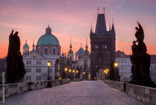 Prague, Czech Republic. Charles Bridge with its statuette and sunrise over the bridge, Old Town Bridge Tower in the background.