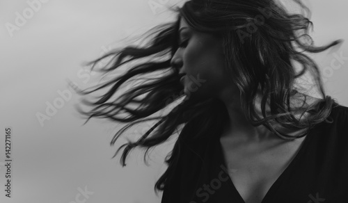 Woman tossing hair at sullen sky background - motion blur