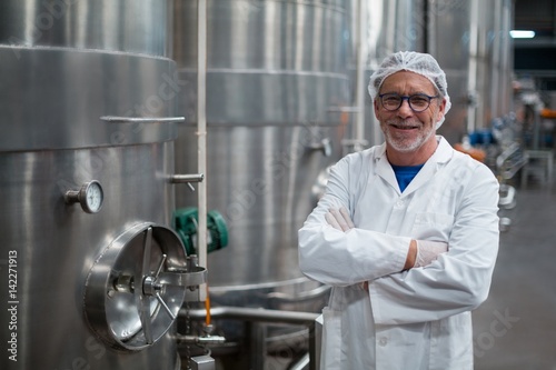 Smiling factory engineer with arms crossed 