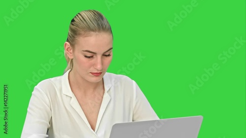 Young blonde businesswoman working on laptop computer on a Green Screen, Chroma Key.