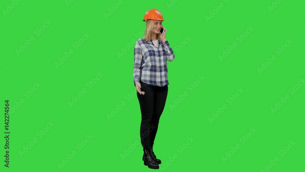 Woman in orange hardhat calling the phone on a Green Screen, Chroma Key. Woman in orange hardhat calling the phone on a Green Screen, Chroma Key.