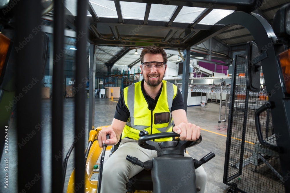 Portrait of smiling factory worker driving forklift Portrait of smiling factory worker driving forklift