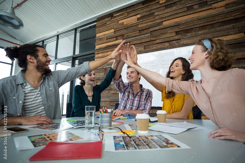 Graphic designers giving high five during meeting Graphic designers giving high five during meeting