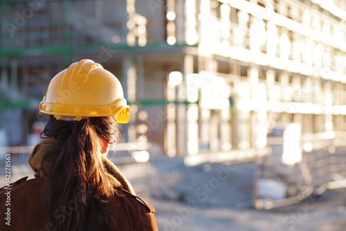 Baugewerbe, Frau mit Schutzhelm und Plänen auf einer Baustelle