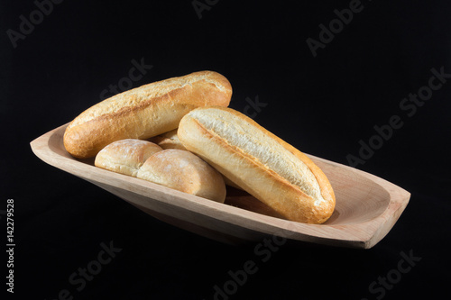 Mini French Baguettes on a rectangular wood bowl with black background photo