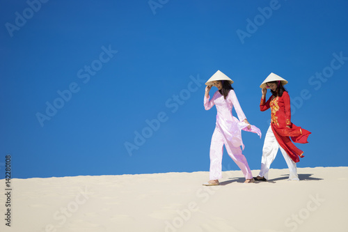 Vietnamese women wearing traditional suit walking in the desert