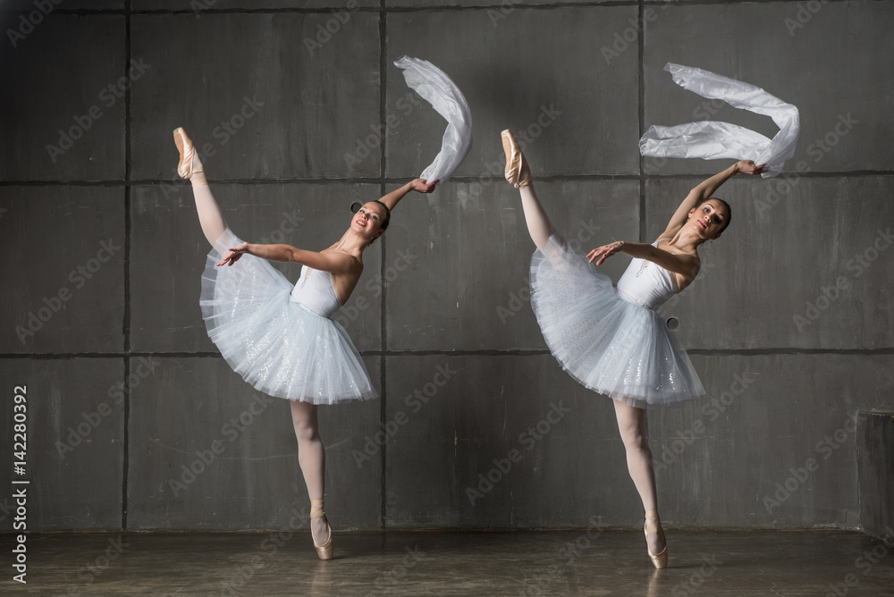Obraz premium Two ballerinas synchronically dancing with white textile