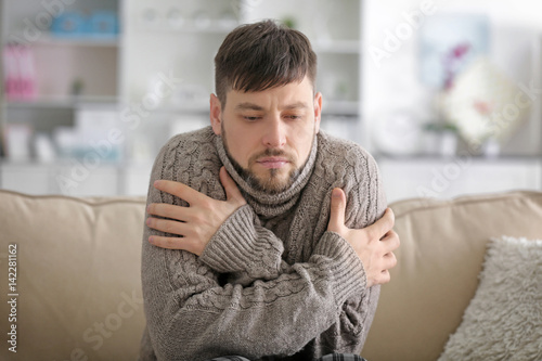 Young ill man sitting on so...