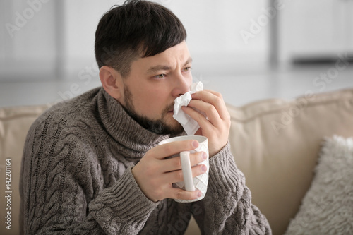 Young ill man drinking hot ...