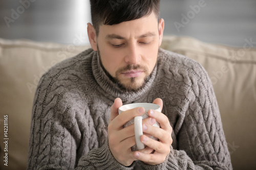 Young ill man drinking hot ...