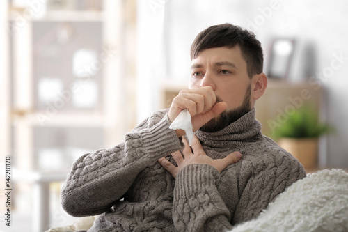 Young ill man sitting on so...