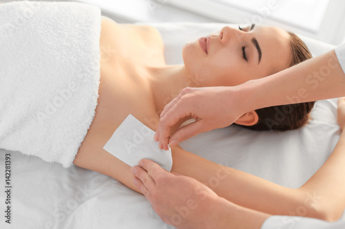 Beautician waxing female armpits in spa center