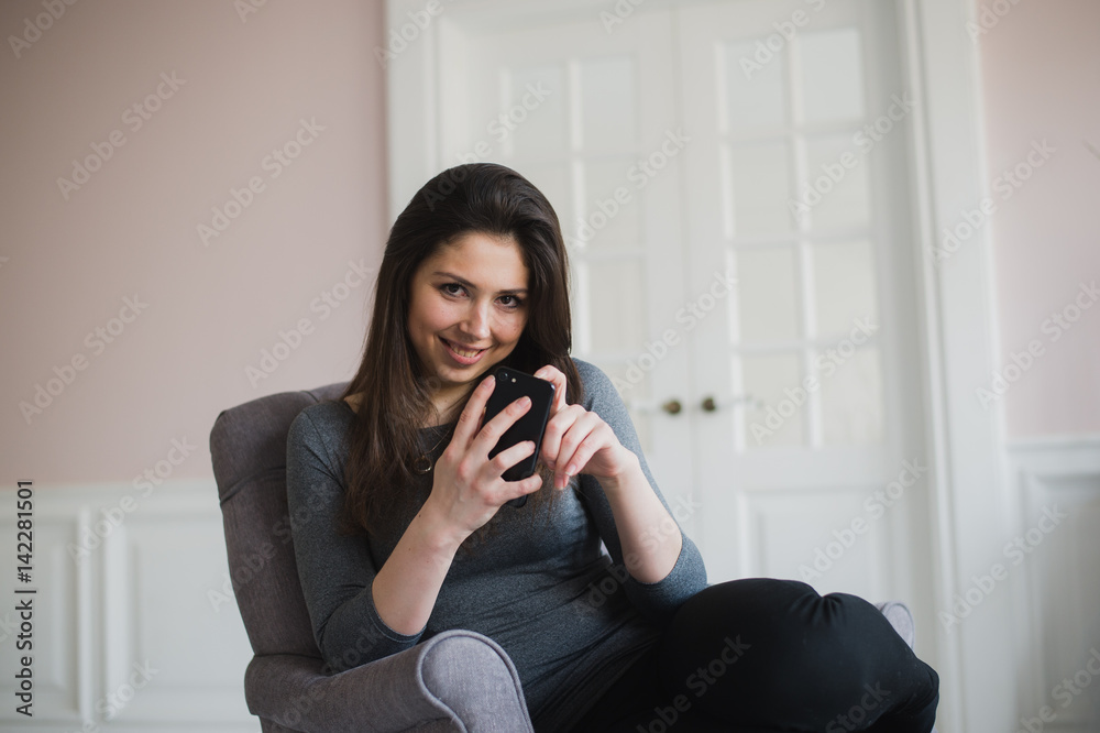 Smiling girl relaxing at home, she is connecting and social networking with her smartphone Smiling girl relaxing at home, she is connecting and social networking with her smartphone