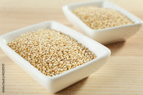 Bowls with quinoa seeds on wooden table