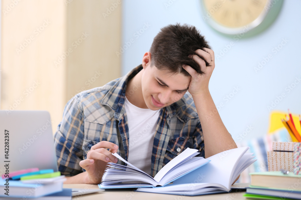 Teenager sitting at table and studying at home Teenager sitting at table and studying at home