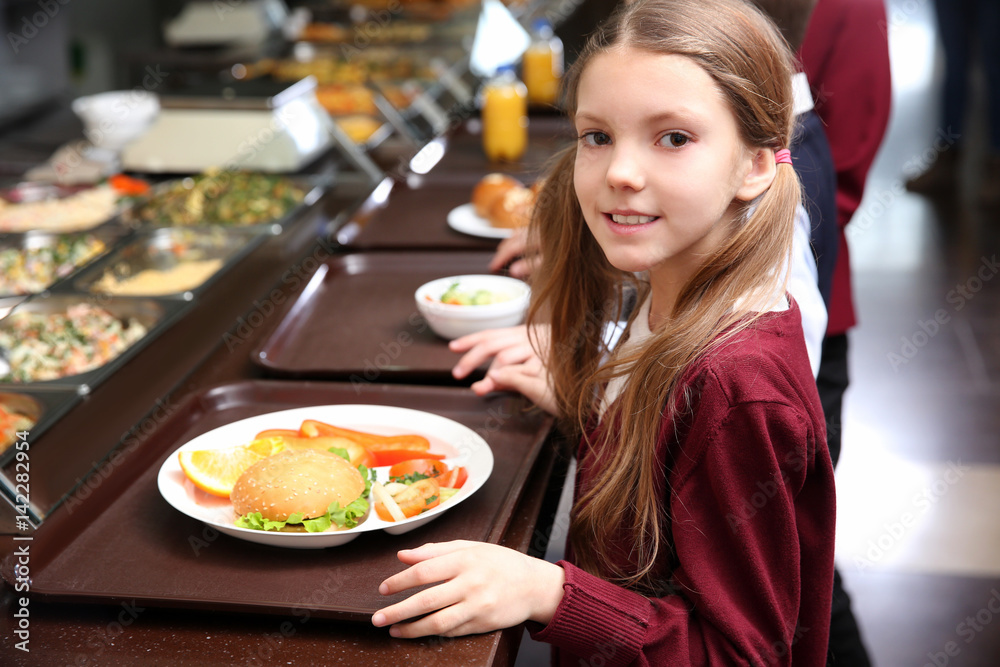 Beautiful little girl receiving food in school cafeteria