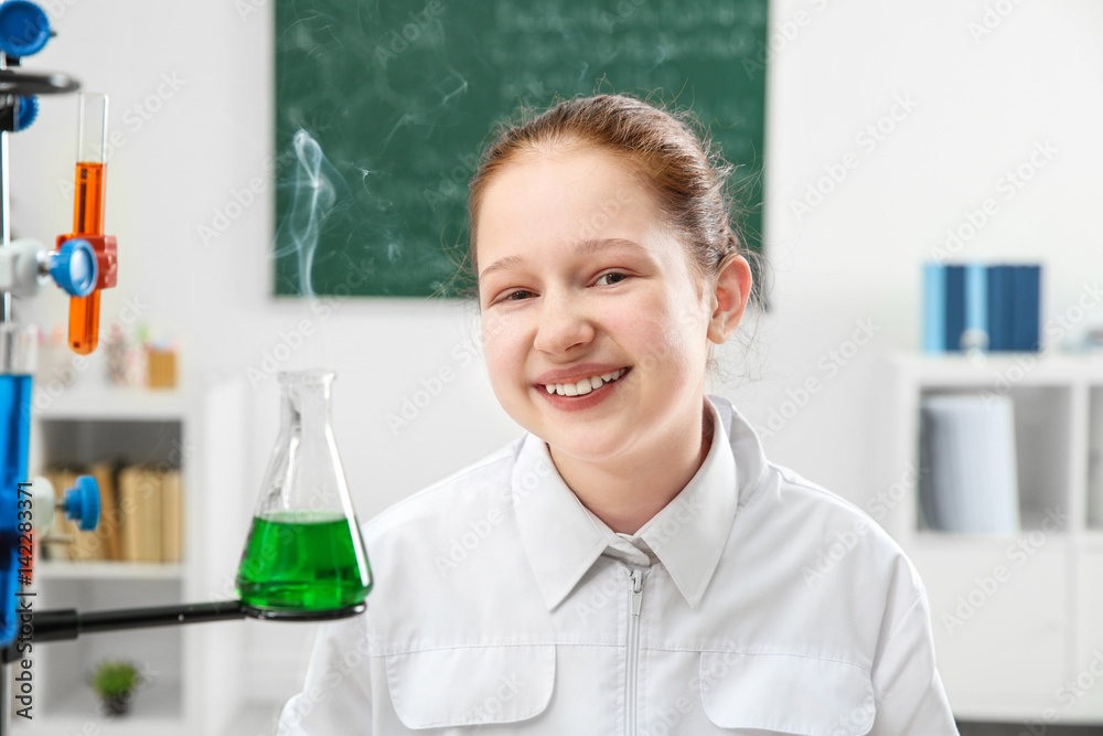 Cheerful school girl looking at flask in chemistry class in chemistry class Cheerful school girl looking at flask in chemistry class in chemistry class
