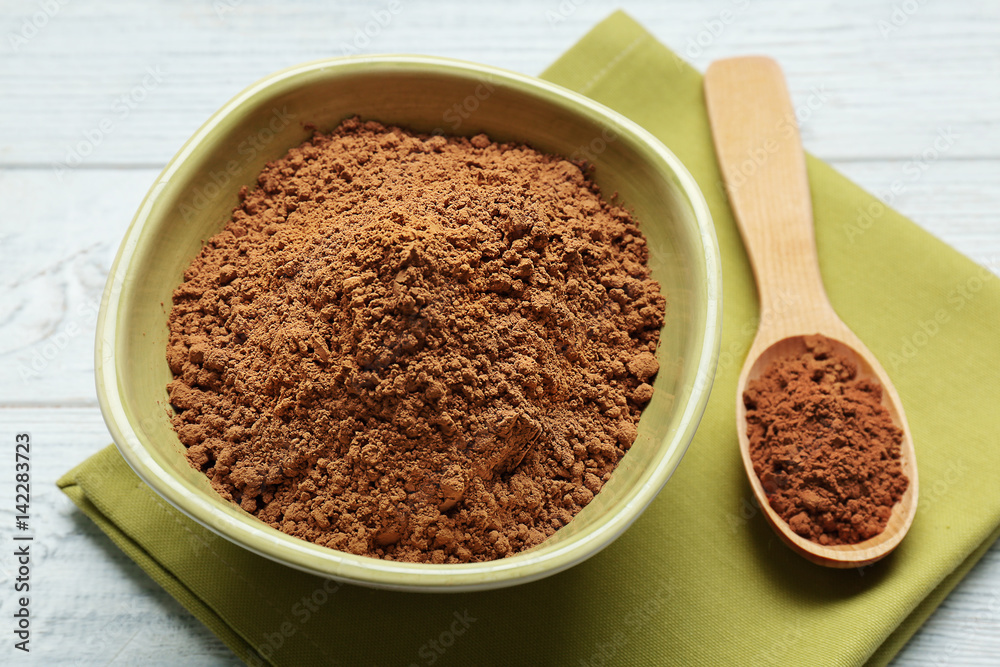 Green plate and wooden spoon with cocoa powder on table Green plate and wooden spoon with cocoa powder on table
