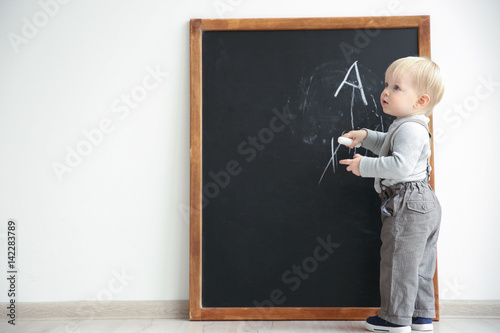 Cute little boy writing on ...