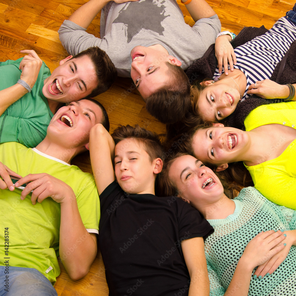 Teenage boys and girls lying on the floor, joking, laughing and having fun
