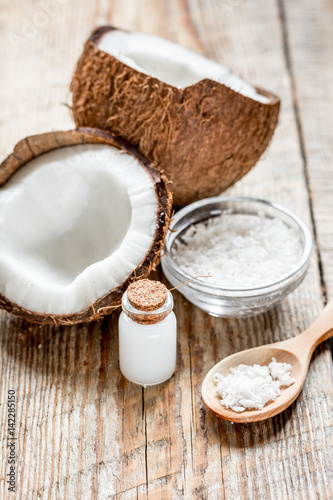 fresh coconut with cosmetic oil in jar on wooden background