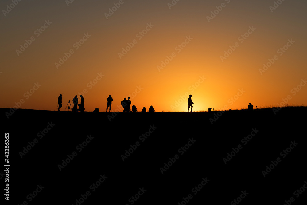 Silhouettes of hikers with backpacks enjoying sunset view
