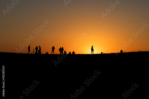 Silhouettes of hikers with backpacks enjoying sunset view