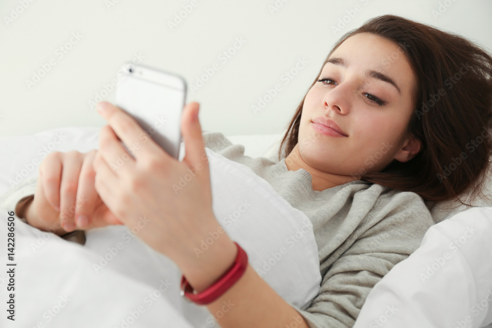 Young woman with sleep tracker and mobile phone lying in bed at home Young woman with sleep tracker and mobile phone lying in bed at home