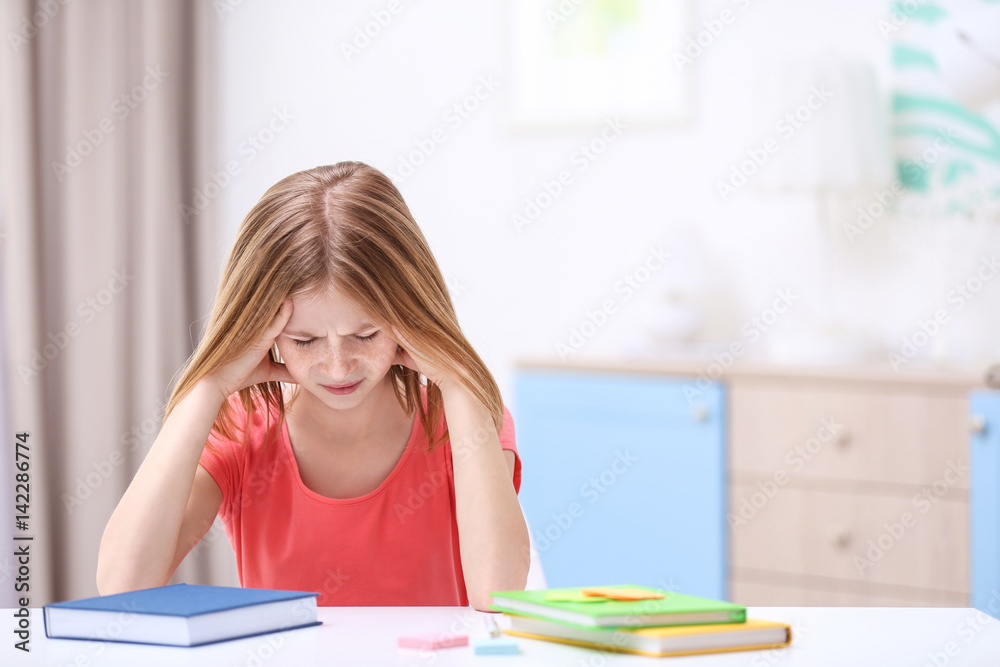 Cute girl suffering from headache while doing lessons at home Cute girl suffering from headache while doing lessons at home