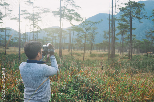 Man taking photos of landscape in the forest at Phu Soi Dao, Uttaradit, Thailand. © Korradol