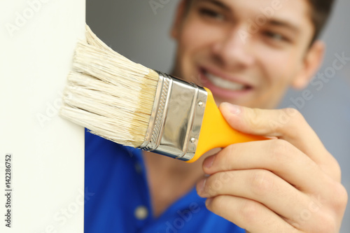 Young man painting window a...