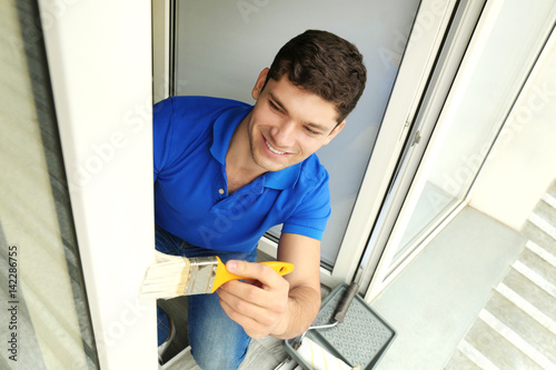 Young man painting window a...