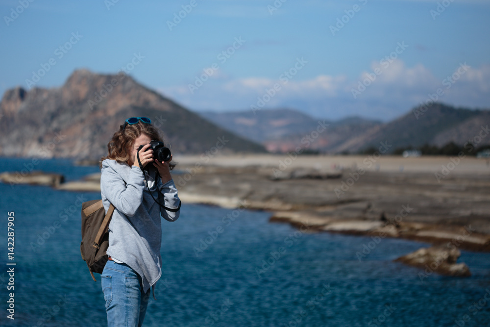 Young woman photographing rock ribbed Koru beach in Gazipasha Al