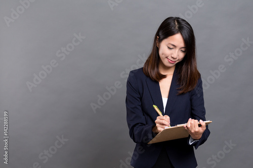 Business woman taking note on clipboard