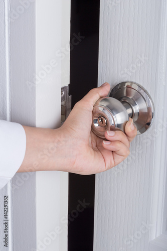 Hand opening door knob on white door
